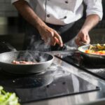 A chef skillfully prepares a meal with fresh ingredients on an electric stove, emphasizing culinary expertise.