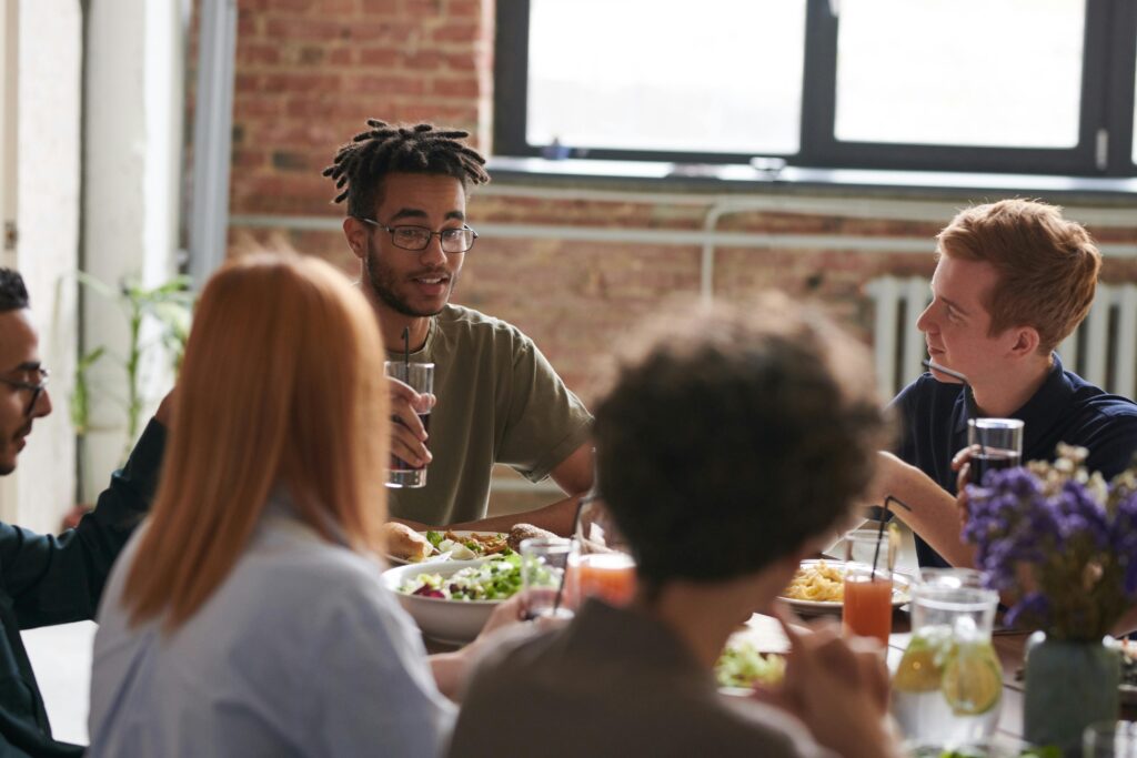 A diverse group of friends sharing a meal and drinks in a cozy restaurant setting.