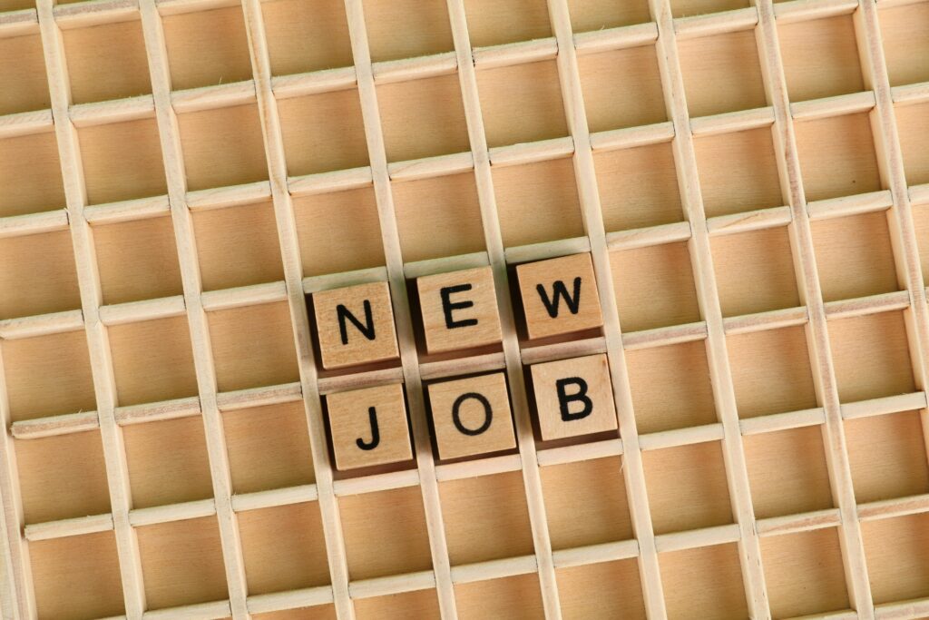 Discover the excitement of a new job with wooden letter tiles spelling 'NEW JOB' on a grid.