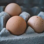 Three fresh brown eggs in a cardboard egg tray, highlighting organic food concepts.