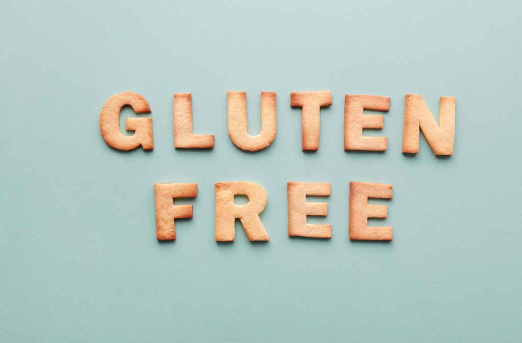 Gluten-free cookie letters form a phrase on a turquoise background, ideal for allergy awareness.