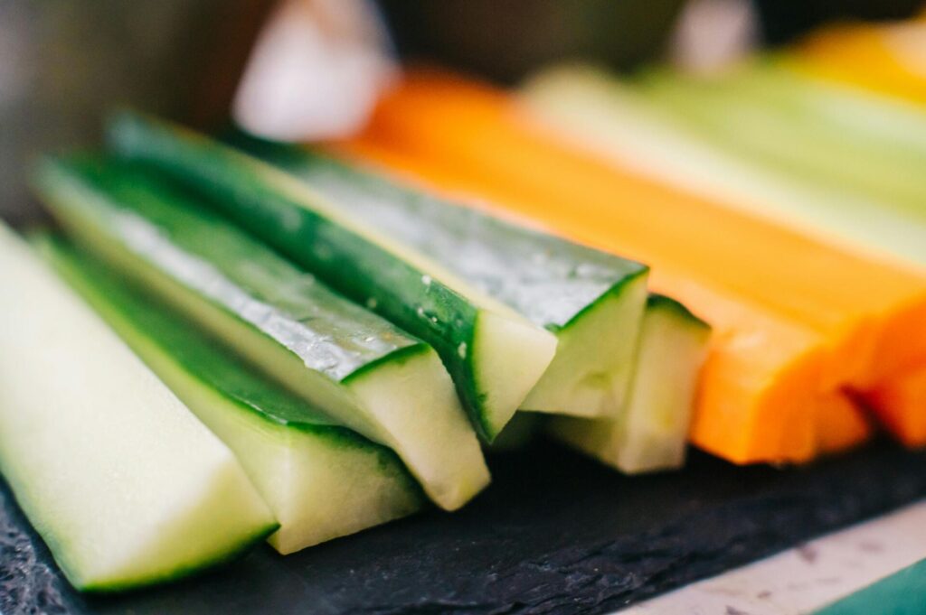 Fresh cucumber and carrot sticks arranged on a slate plate, ready for snacking.